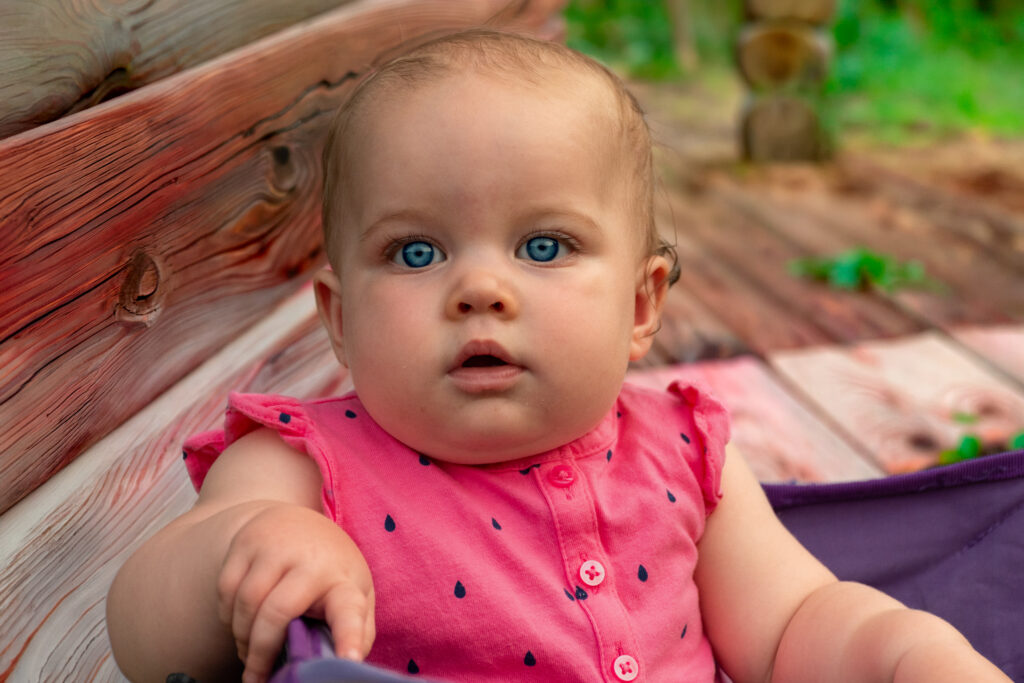 Blue Eyed Baby in Pink Shirt Sitting in Purple Cart
