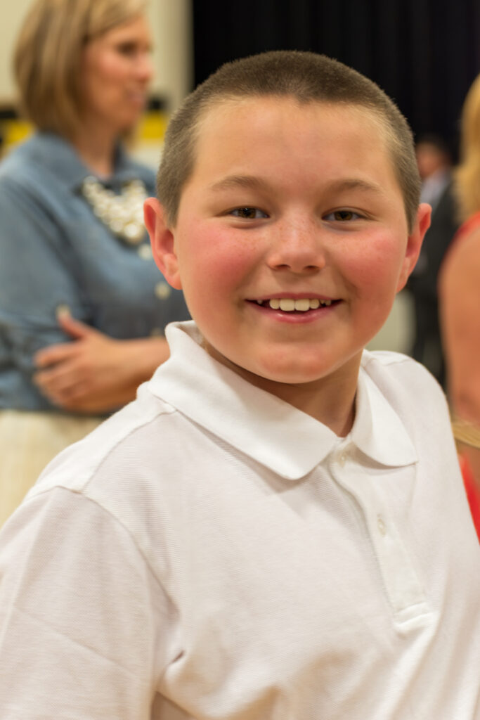 Boy in White Shirt Smiling at a Ceremony