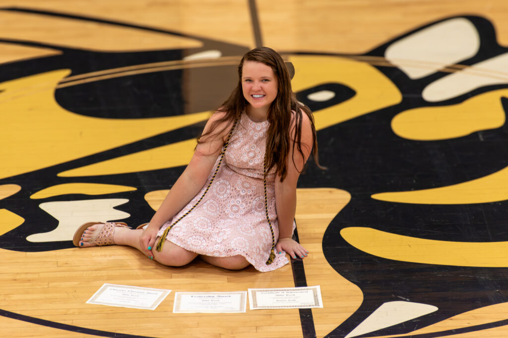 Girl in Dress at Graduation on Gym Floor with Mascot